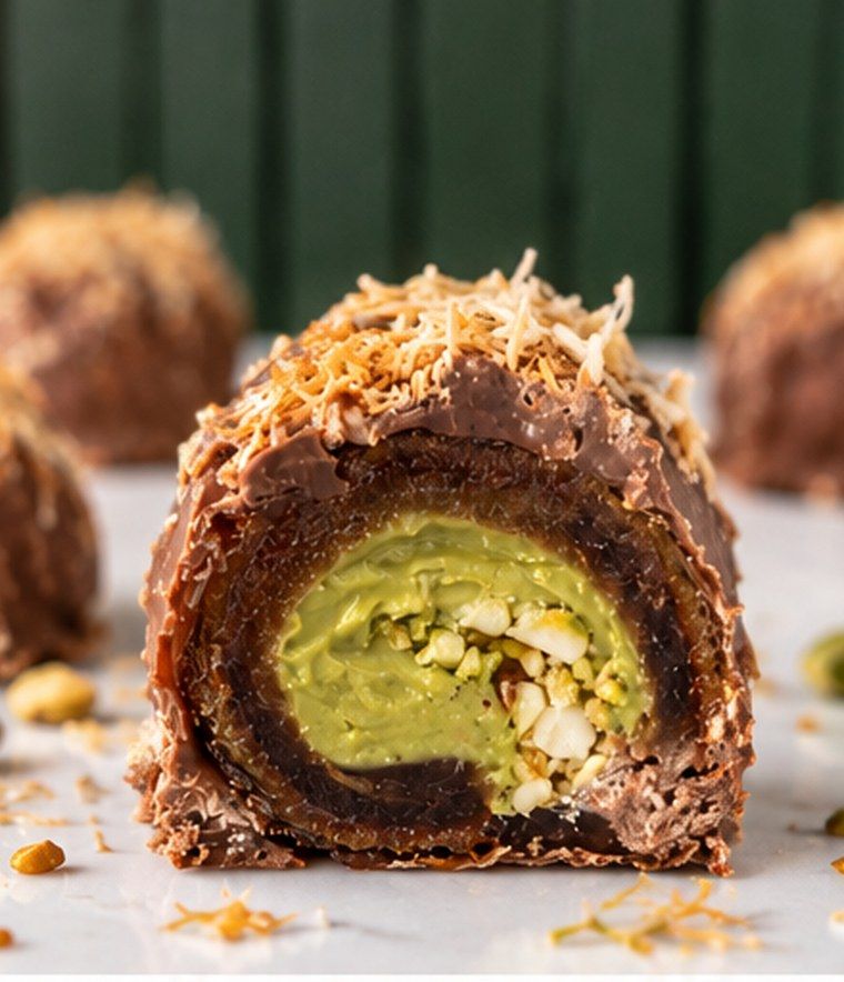 A stuffed date split open, pistachio filling showing